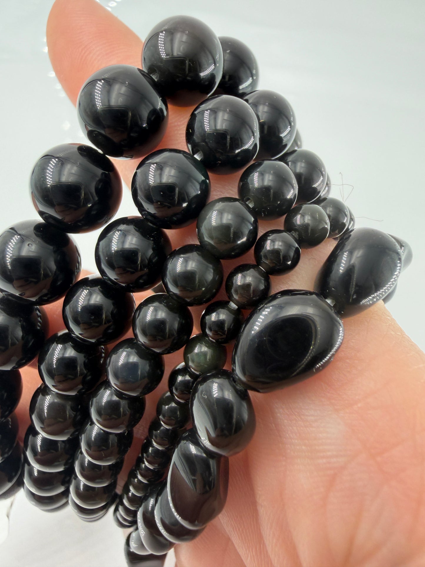 Kugelarmband aus Regenbogen-Obsidian mit irisierenden Farbringen in Violett und Grün.