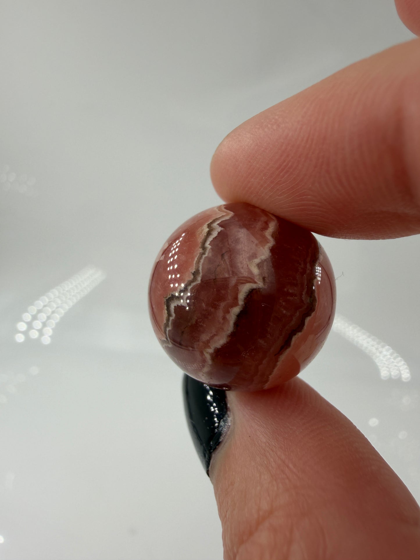 Polierte Kugel aus Rhodochrosit mit leuchtend rosa konzentrischen Bändern, Durchmesser 1,9 cm.