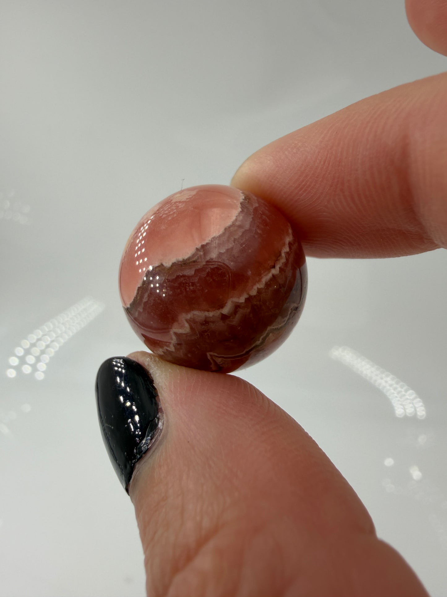 Polierte Kugel aus Rhodochrosit mit leuchtend rosa konzentrischen Bändern, Durchmesser 1,9 cm.