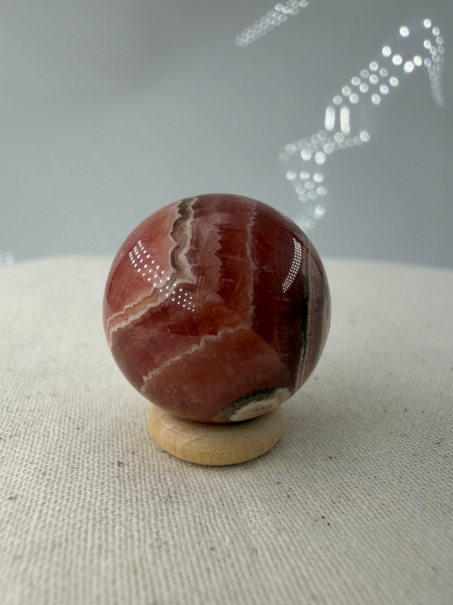 Polierte Kugel aus Rhodochrosit mit leuchtend rosa konzentrischen Bändern, Durchmesser 2,2 cm.