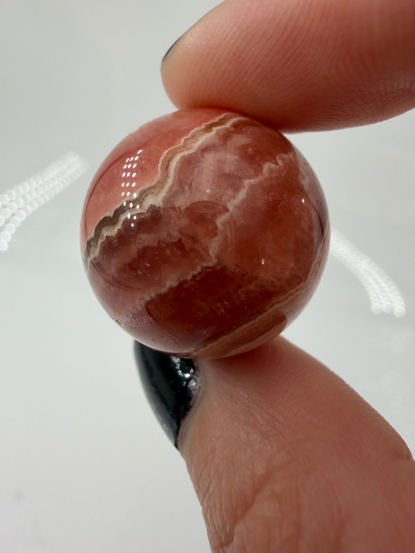 Polierte Kugel aus Rhodochrosit mit leuchtend rosa konzentrischen Bändern, Durchmesser 2,2 cm.