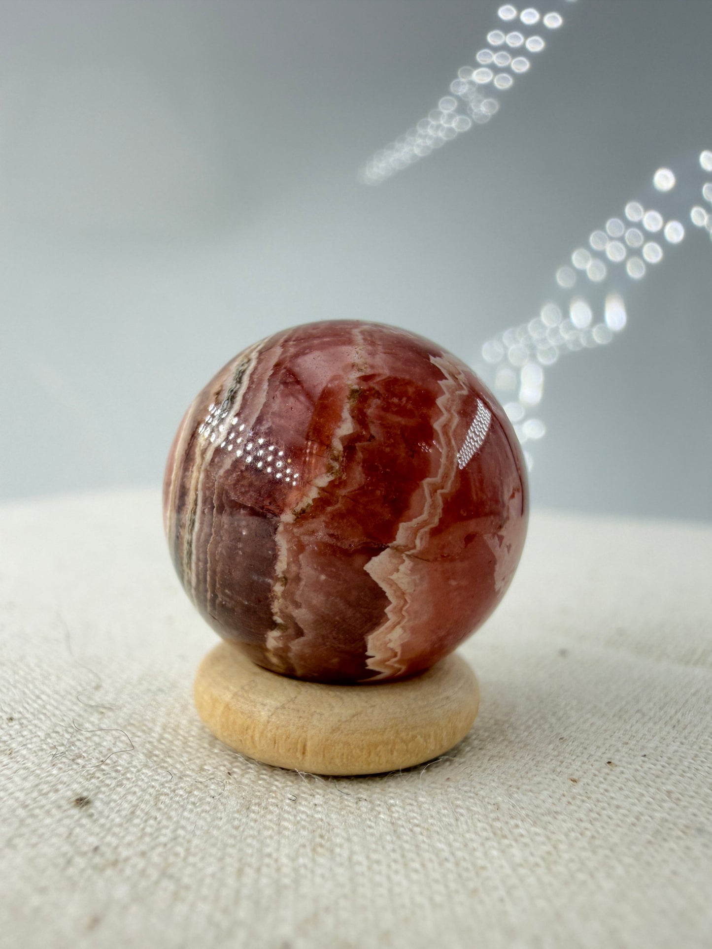 Polierte Kugel aus Rhodochrosit mit leuchtend rosa konzentrischen Bändern, Durchmesser 1,8 cm.