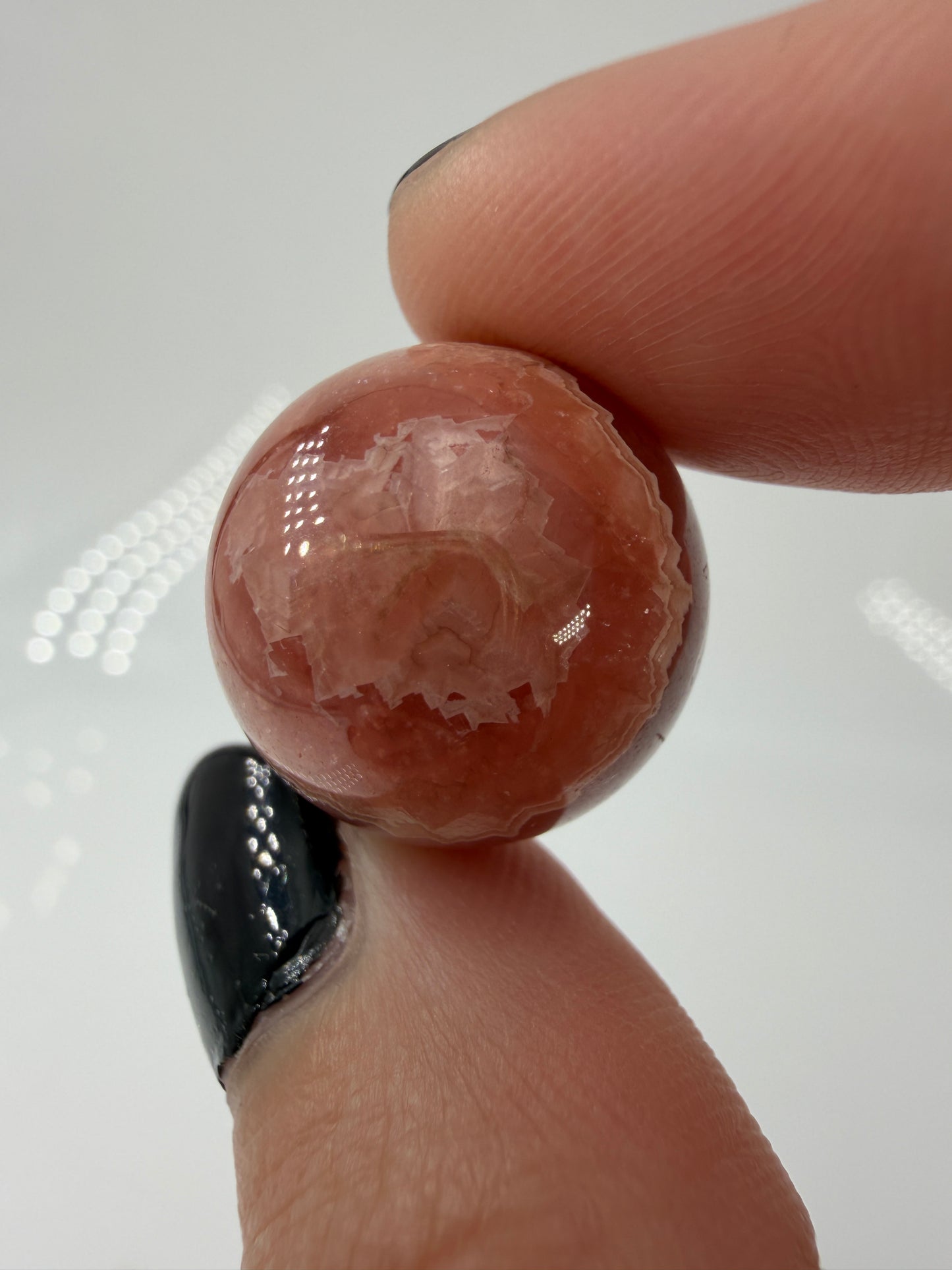 Polierte Kugel aus Rhodochrosit mit leuchtend rosa konzentrischen Bändern, Durchmesser 1,8 cm.