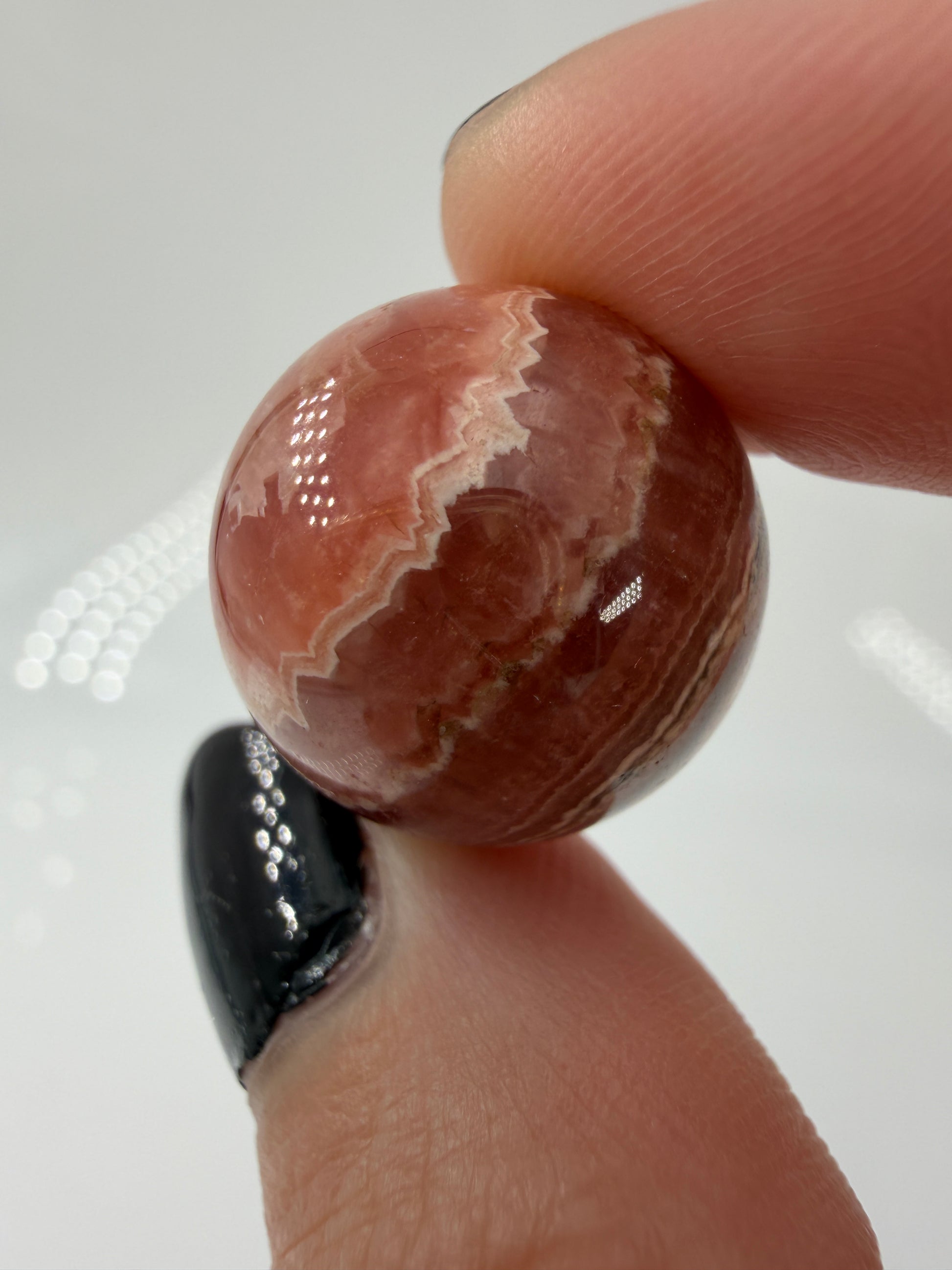 Polierte Kugel aus Rhodochrosit mit leuchtend rosa konzentrischen Bändern, Durchmesser 1,8 cm.