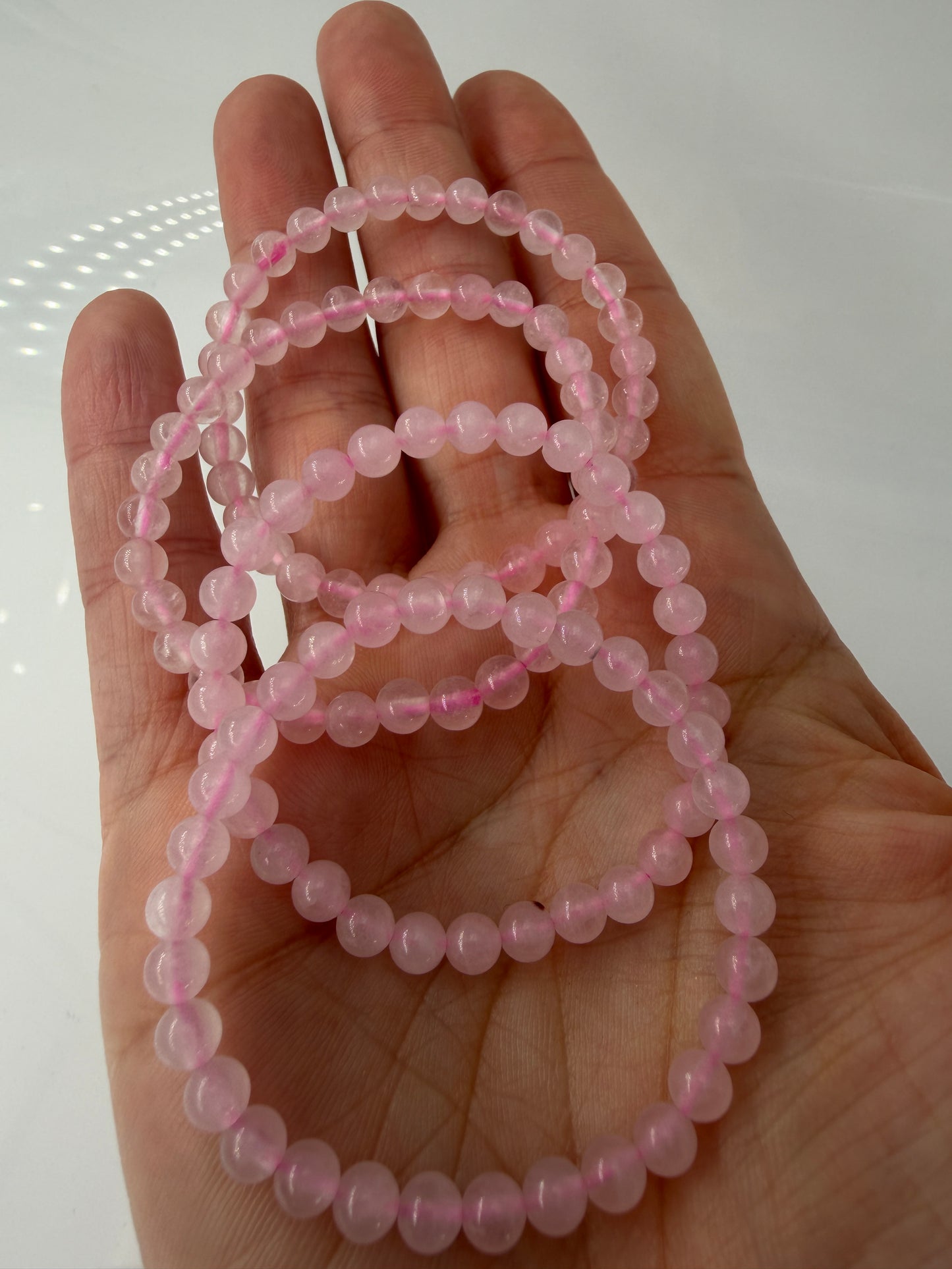 Zartrosa Kugelarmband aus poliertem Rosenquarz auf elastischem Band für Kinder.