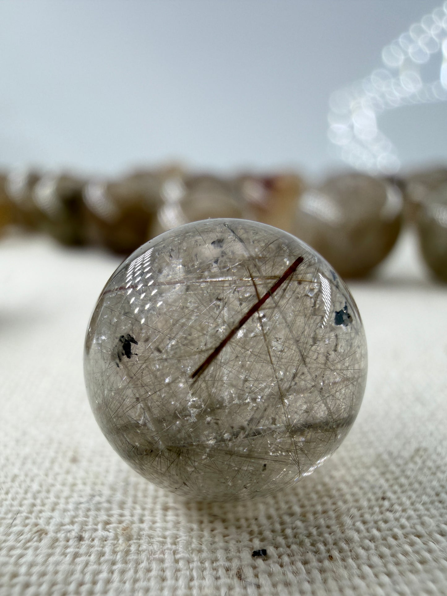 Rutil Minikugel mit seidigem Metallglanz und nadelförmigen Einschlüssen, tetragonale Kristallstruktur sichtbar, Ø ca. 1,1 cm.