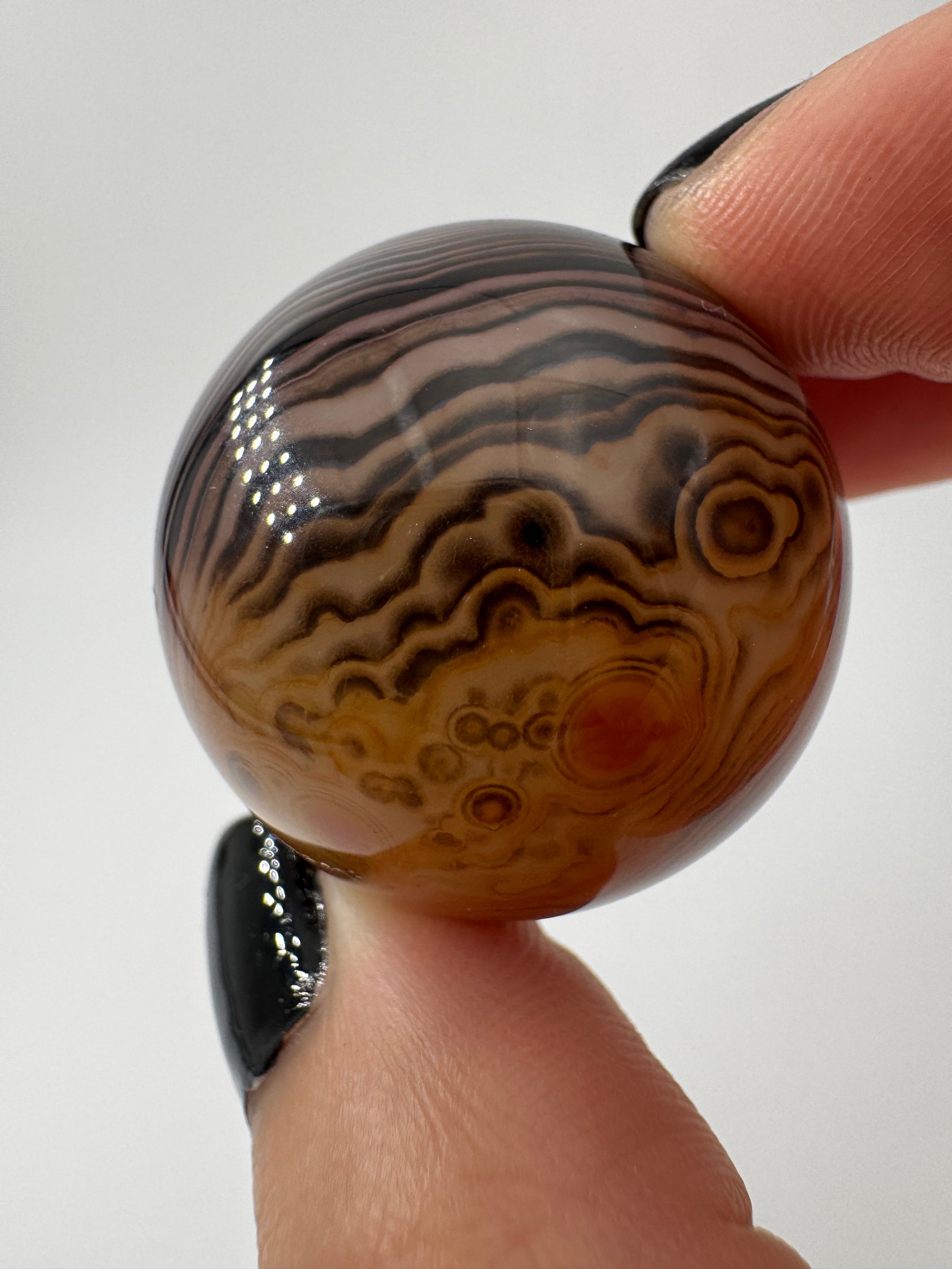 Eine hochglanzpolierte Kugel aus Sardonyx mit charakteristischer Bänderung.