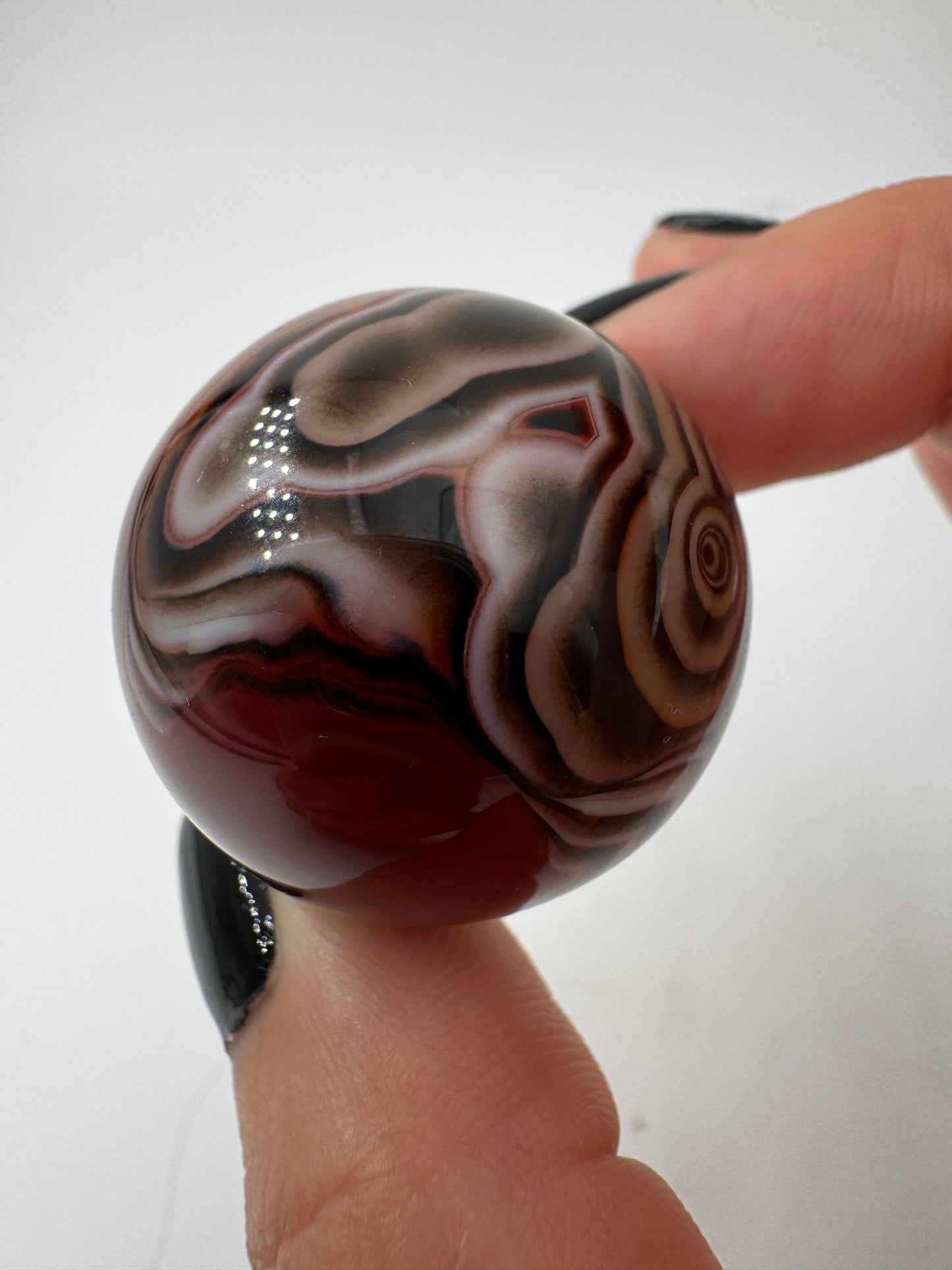 Eine hochglanzpolierte Kugel aus Sardonyx mit charakteristischer Bänderung.
