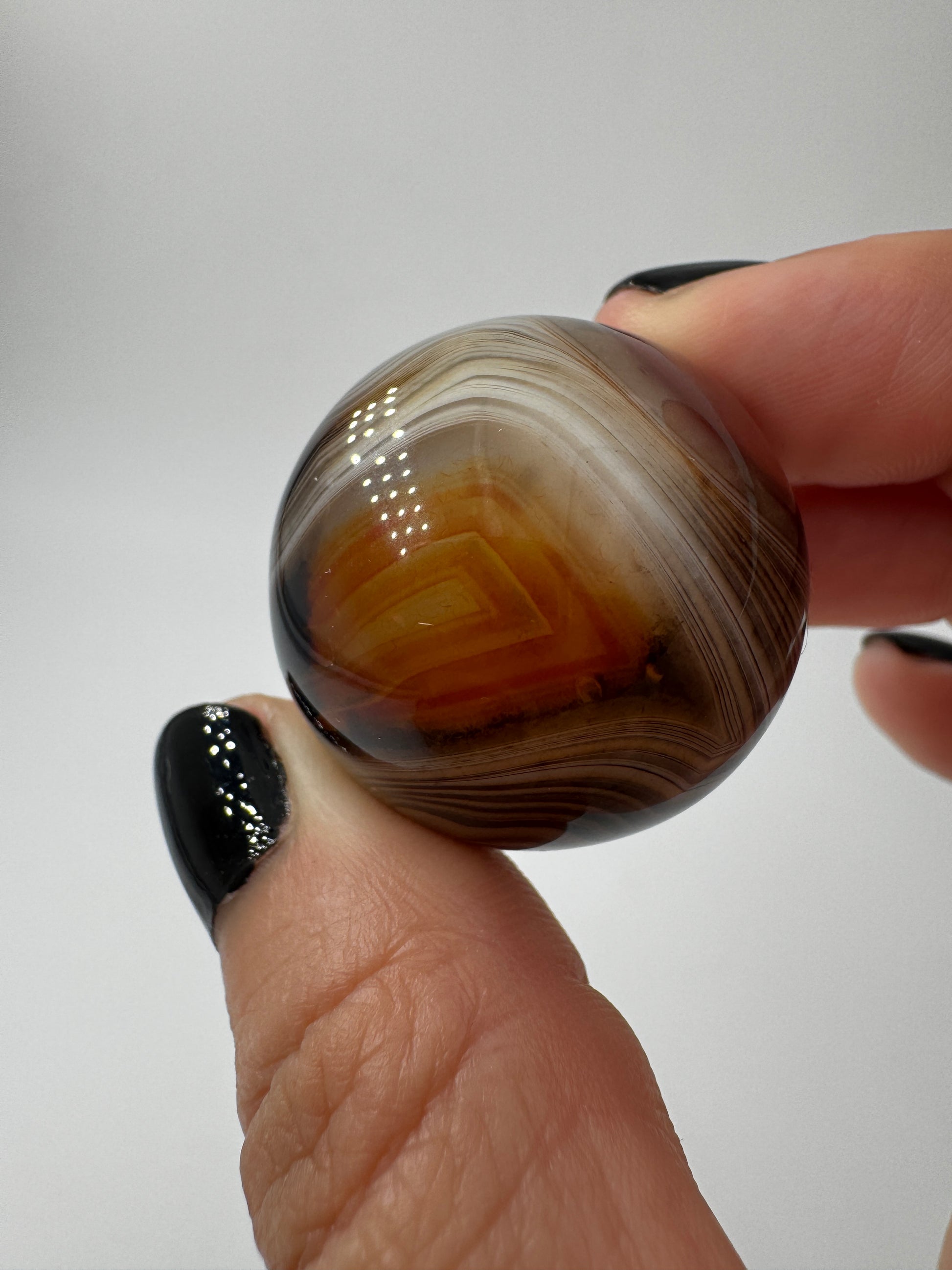 Eine hochglanzpolierte Kugel aus Sardonyx mit charakteristischer Bänderung.
