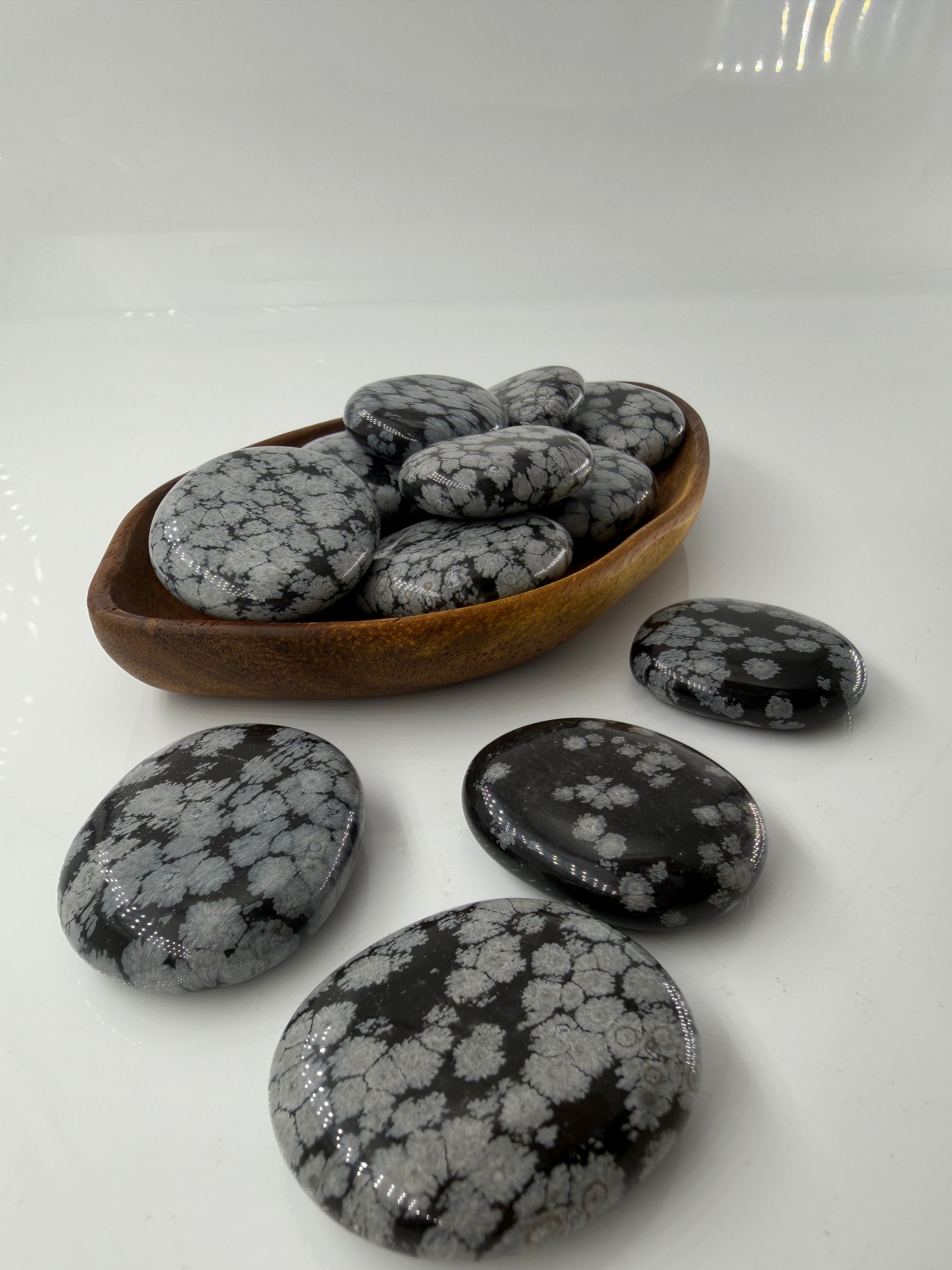 Flacher Scheibenstein aus Schneeflocken-Obsidian mit markanten weißen Cristobalit-Flocken auf schwarzer Glasmatrix.
