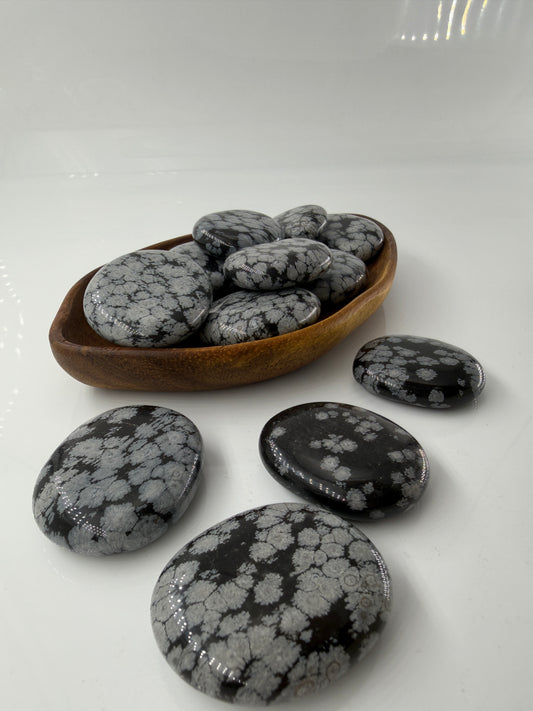 Flacher Scheibenstein aus Schneeflocken-Obsidian mit markanten weißen Cristobalit-Flocken auf schwarzer Glasmatrix.