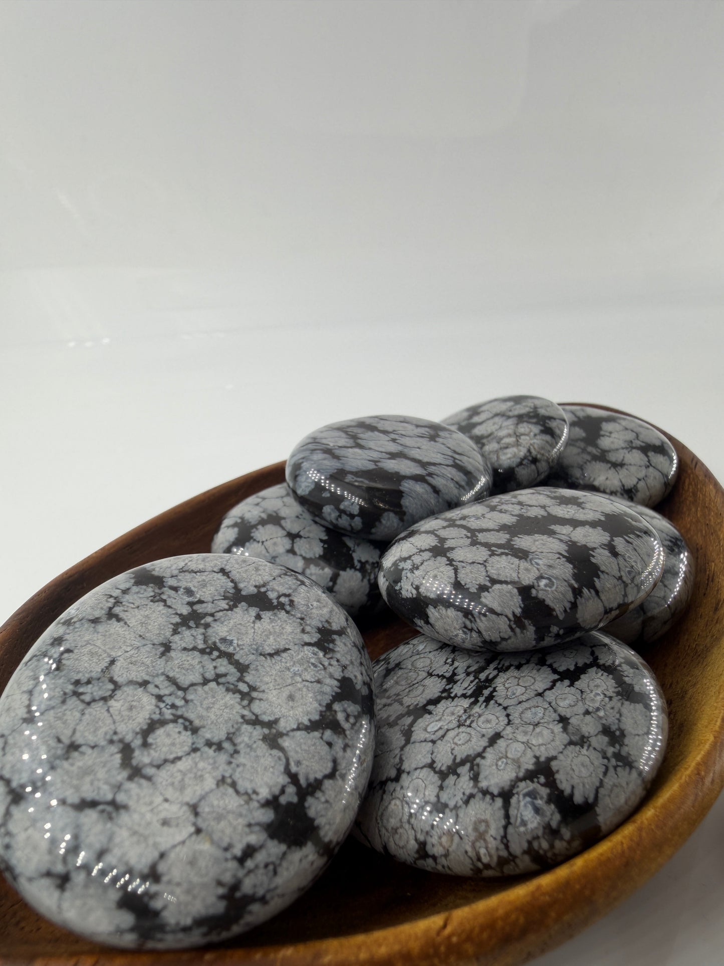 Flacher Scheibenstein aus Schneeflocken-Obsidian mit markanten weißen Cristobalit-Flocken auf schwarzer Glasmatrix.