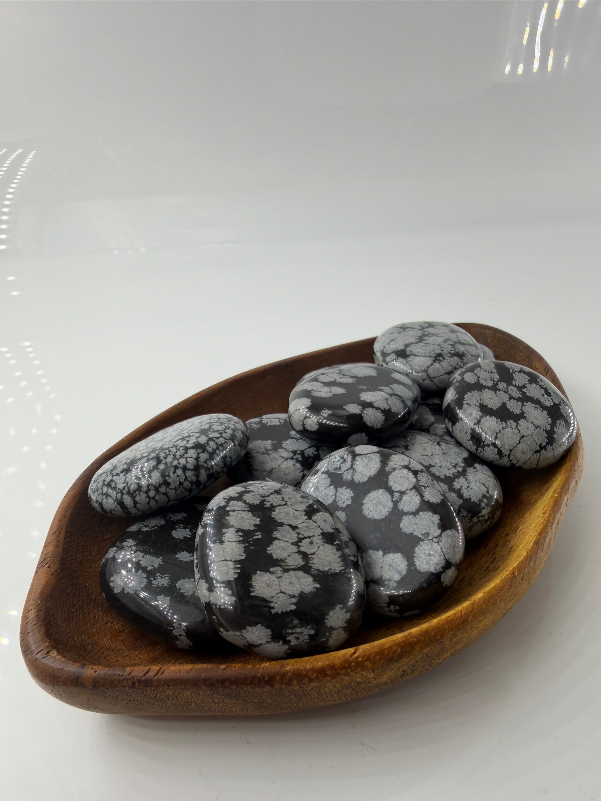 Flacher Scheibenstein aus Schneeflocken-Obsidian mit markanten weißen Cristobalit-Flocken auf schwarzer Glasmatrix.