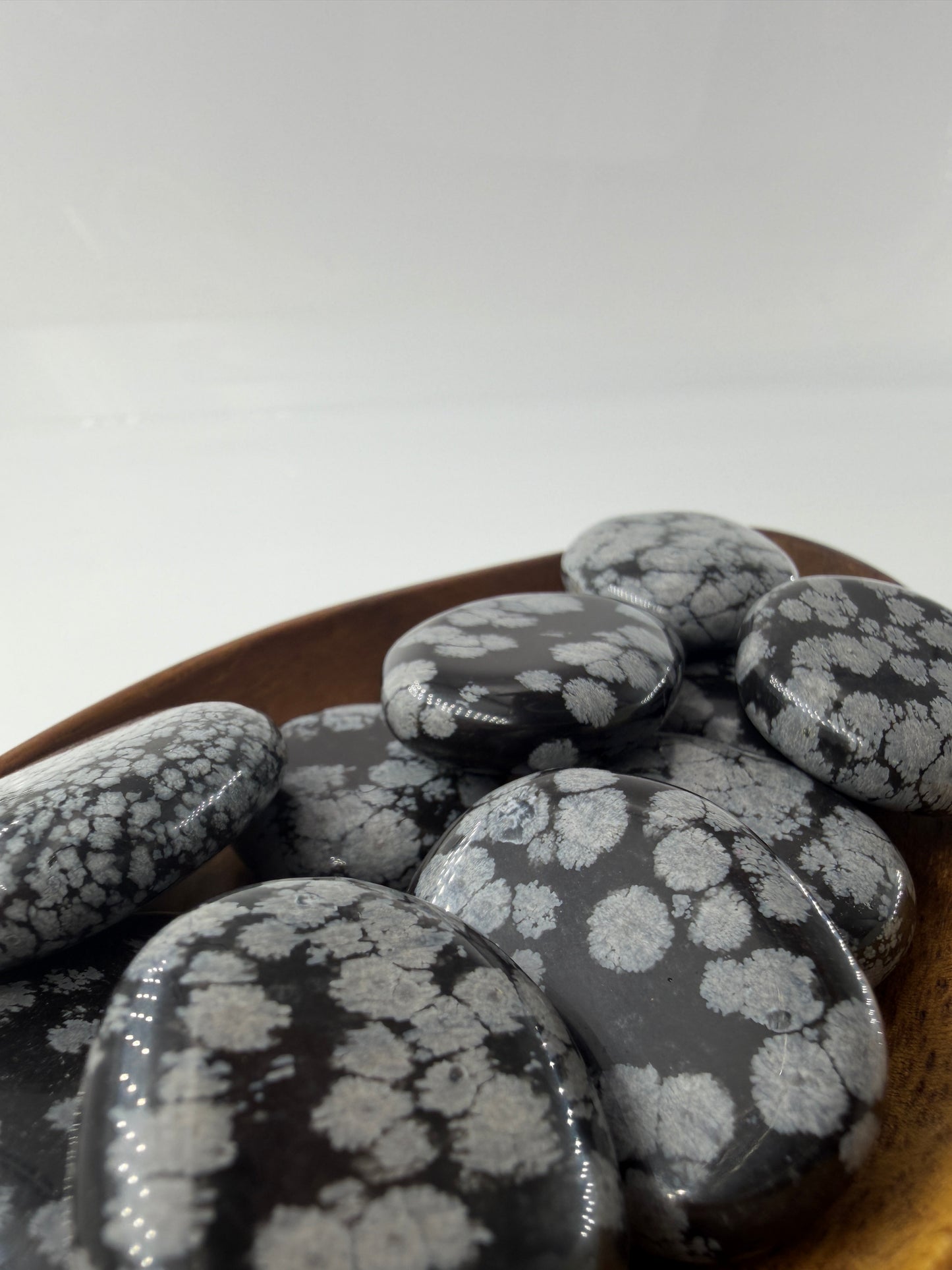 Flacher Scheibenstein aus Schneeflocken-Obsidian mit markanten weißen Cristobalit-Flocken auf schwarzer Glasmatrix.
