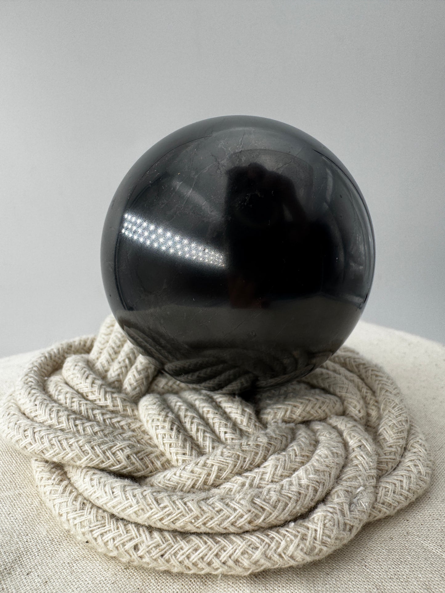 Eine perfekt runde, tiefschwarze Kugel aus poliertem Shungit.