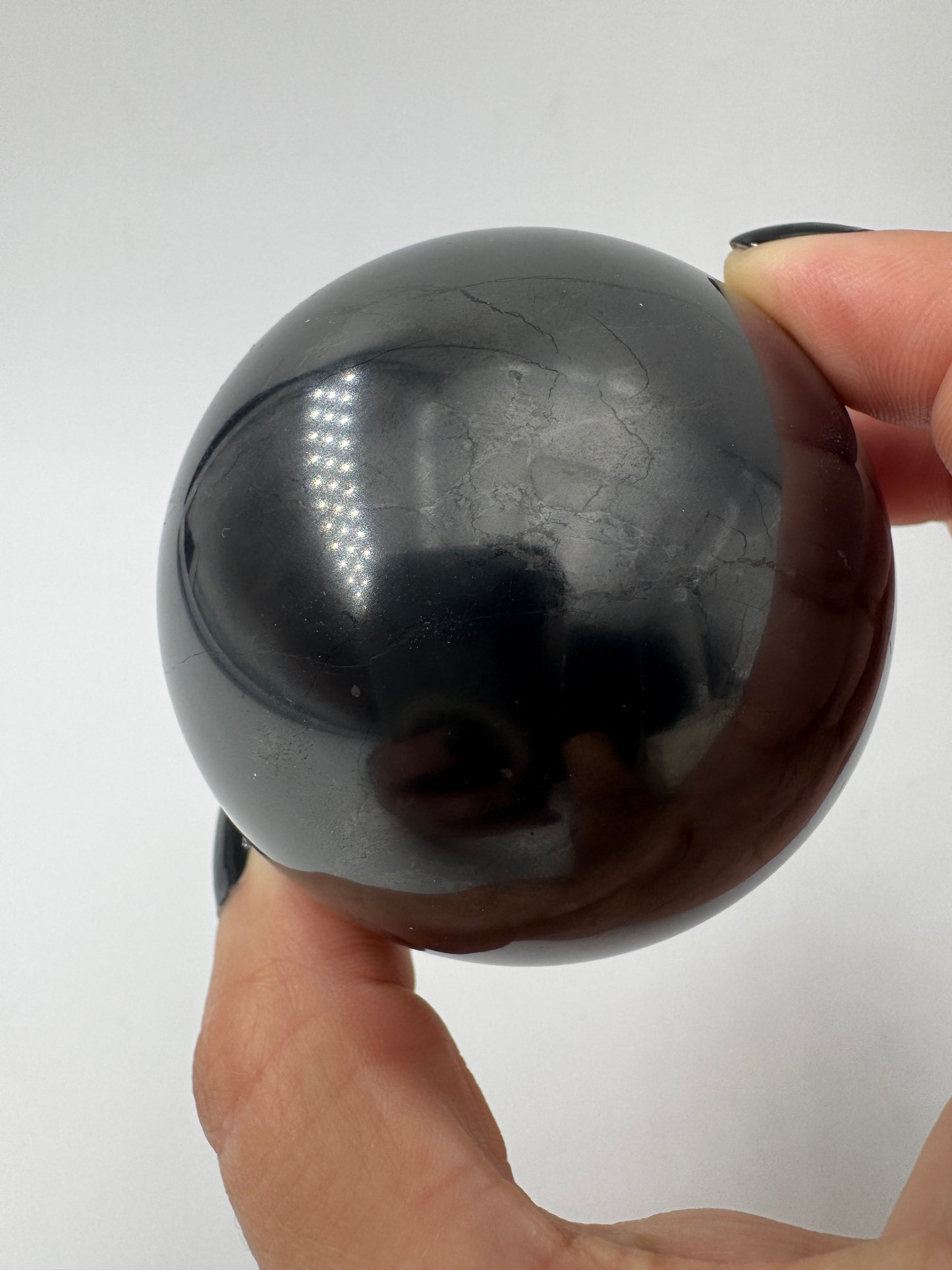 Eine perfekt runde, tiefschwarze Kugel aus poliertem Shungit.