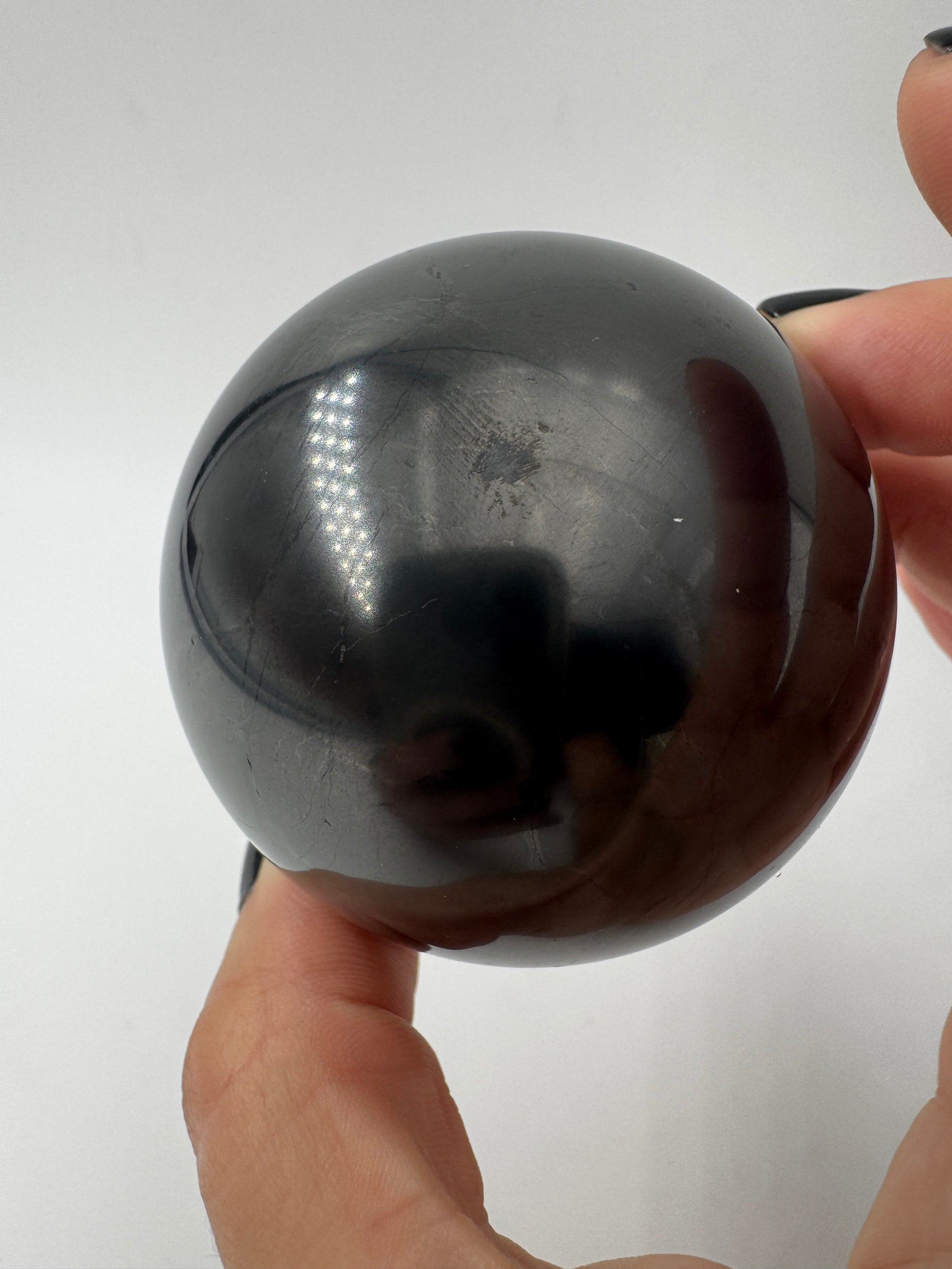 Eine perfekt runde, tiefschwarze Kugel aus poliertem Shungit.