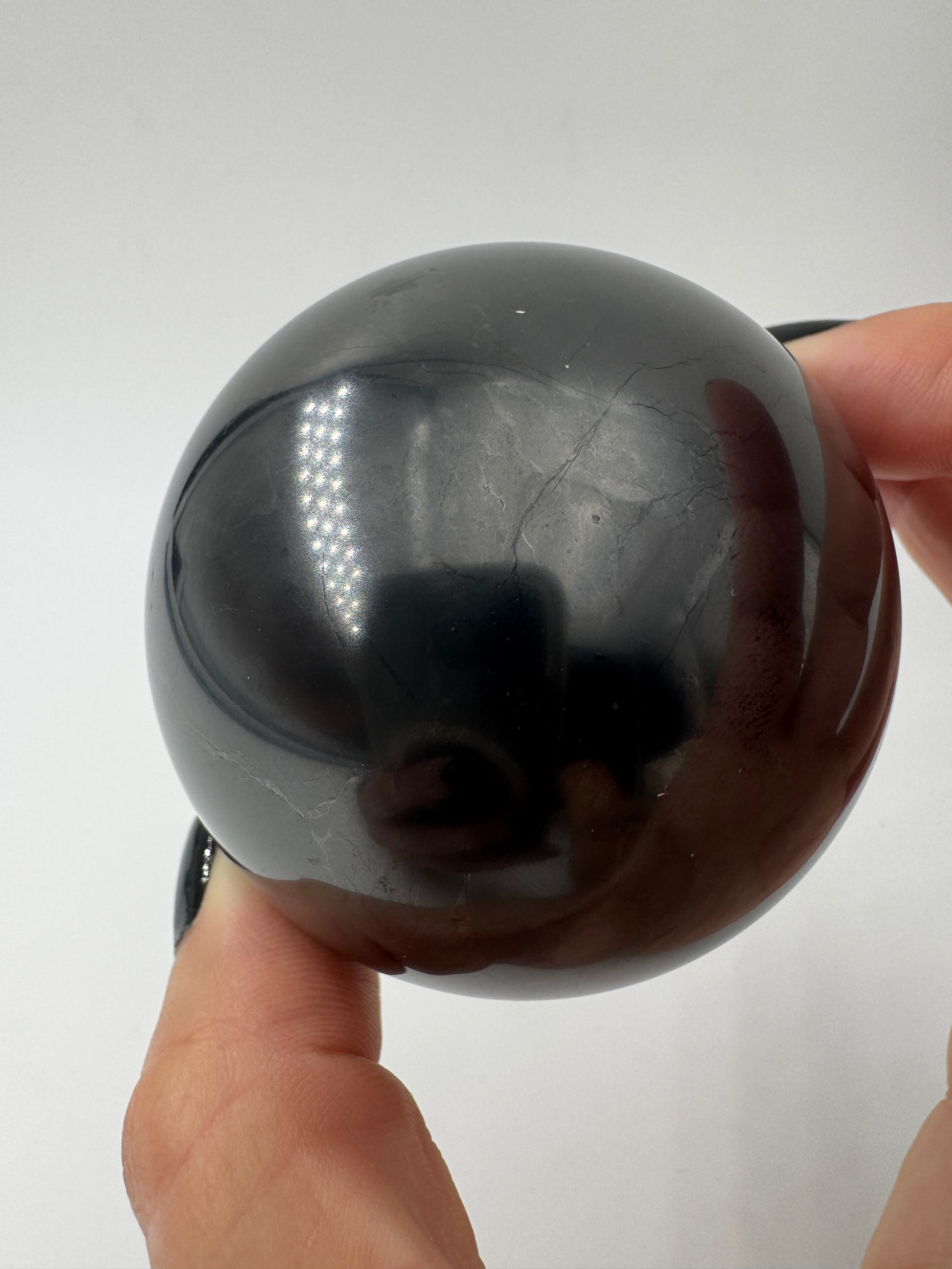 Eine perfekt runde, tiefschwarze Kugel aus poliertem Shungit.