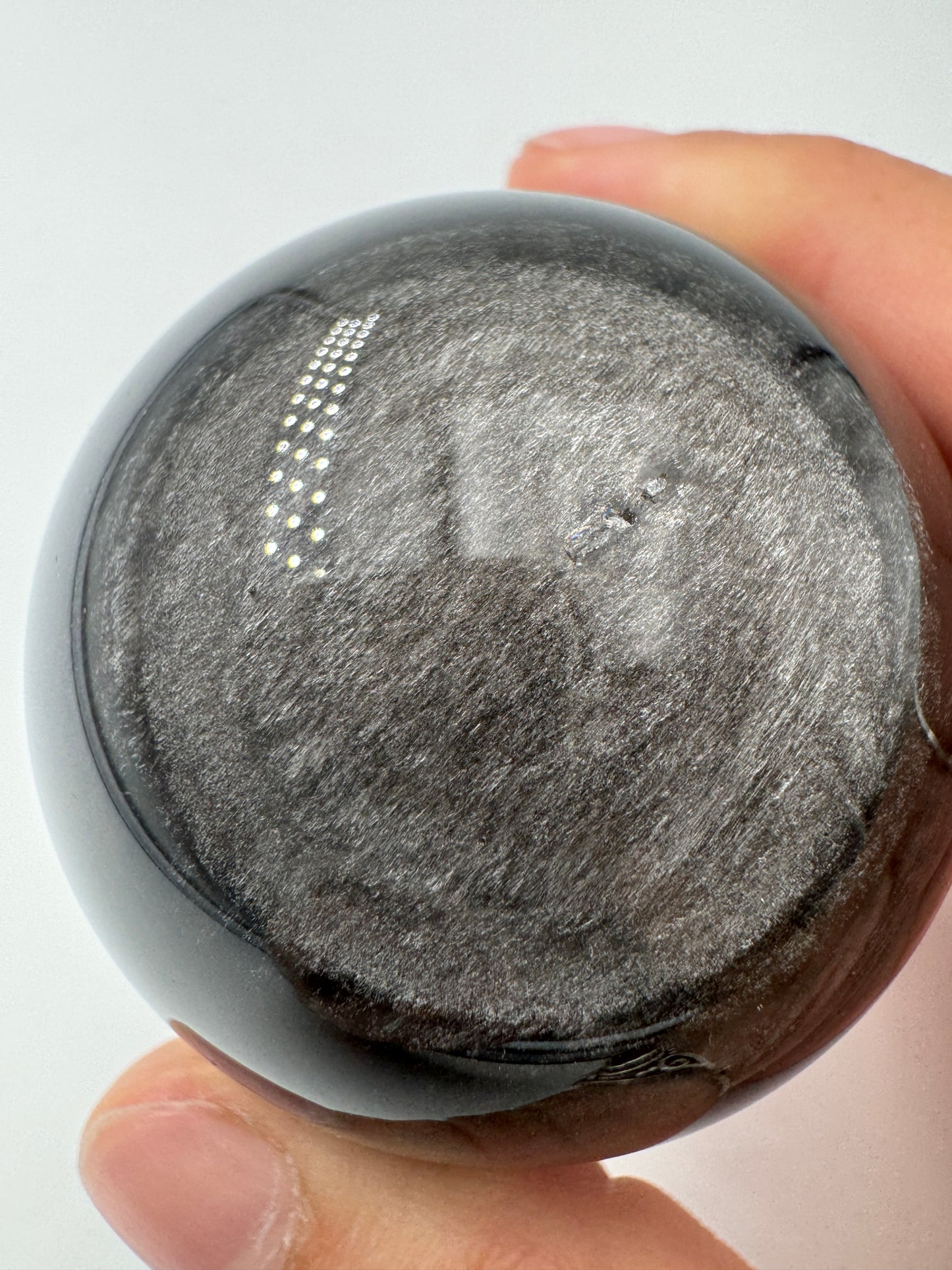 Polierte Silberobsidian Kugel, Ø 5,2 cm, mit charakteristischem silbrigem Seidenglanz auf schwarzem vulkanischem Glas.
