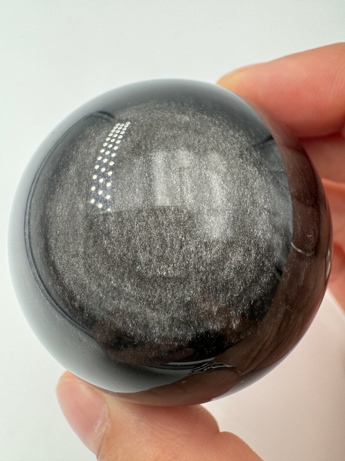 Polierte Silberobsidian Kugel, Ø 5,2 cm, mit charakteristischem silbrigem Seidenglanz auf schwarzem vulkanischem Glas.
