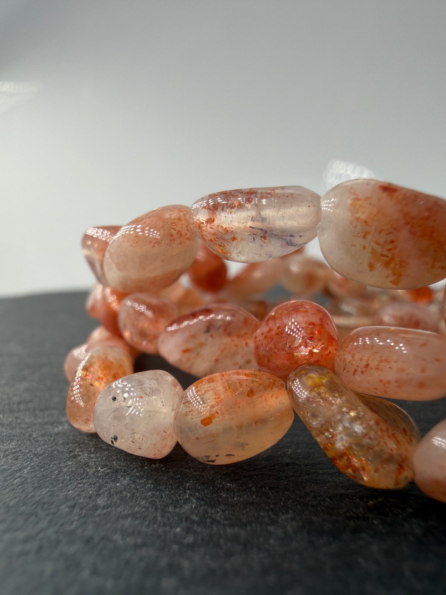 Splitterarmband aus schimmerndem Sonnenstein mit warmen Orangetönen und feinen metallischen Reflexen.