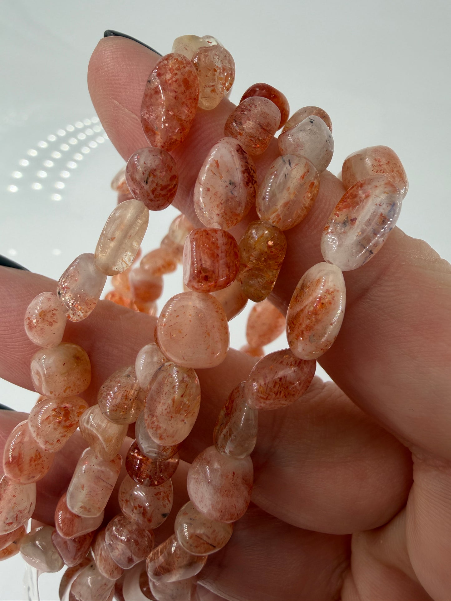 Splitterarmband aus schimmerndem Sonnenstein mit warmen Orangetönen und feinen metallischen Reflexen.