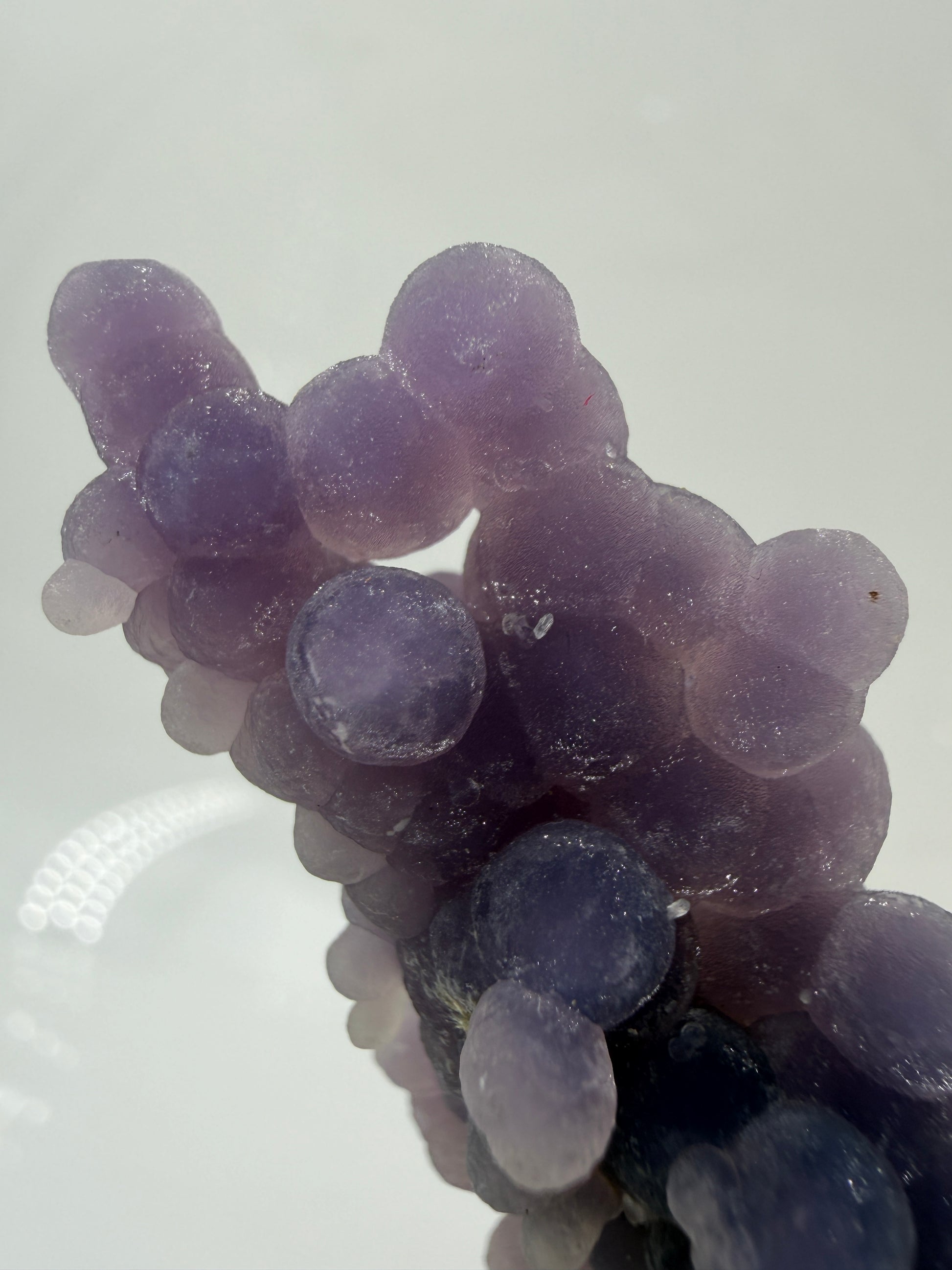 INahaufnahme der traubenförmigen Struktur von lila Chalcedon, zeigt den glitzernden Drusy-Quarz-Überzug auf den Sphären.