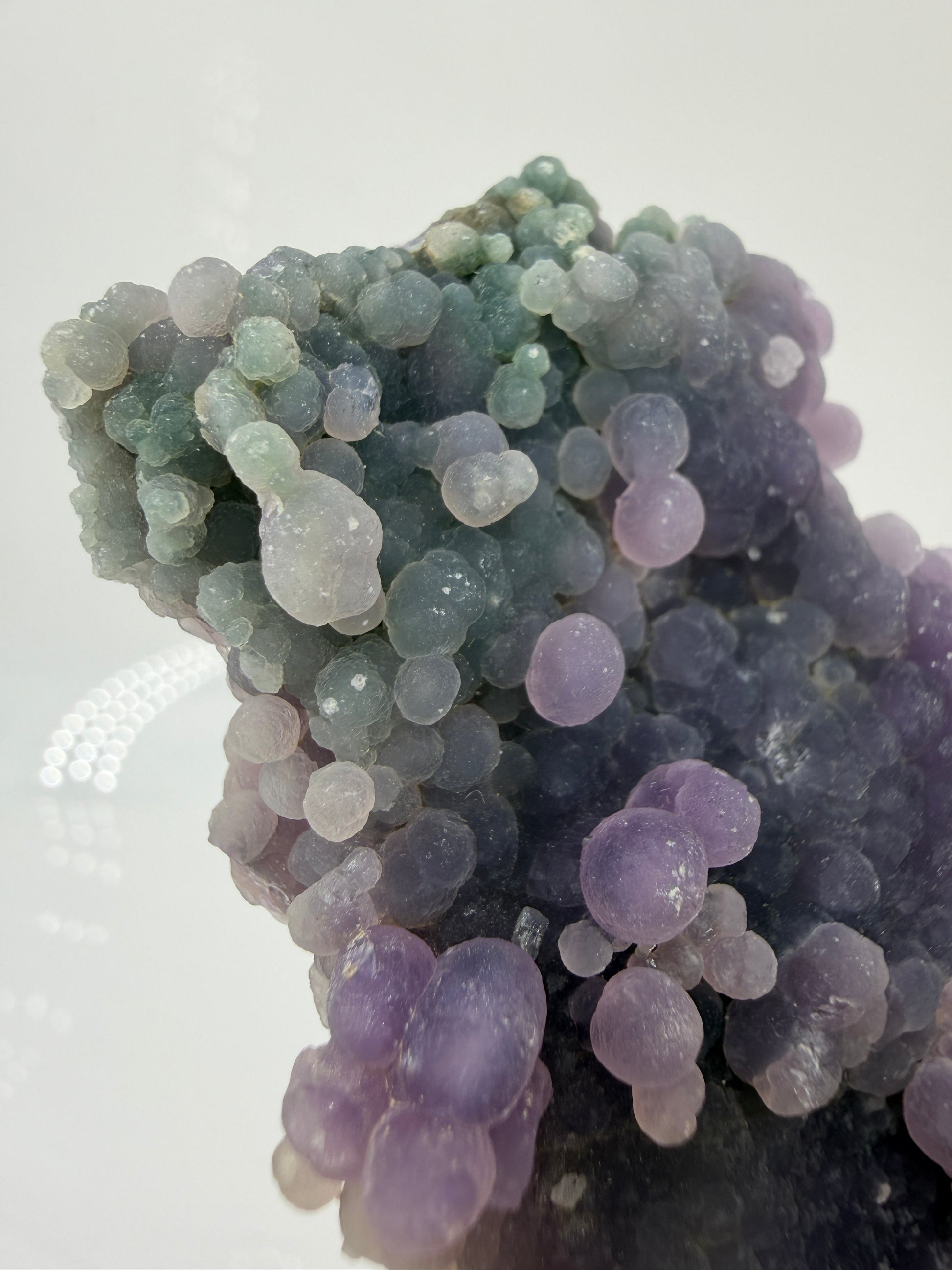 Nahaufnahme der traubenförmigen Struktur von lila/grün Chalcedon, zeigt den glitzernden Drusy-Quarz-Überzug auf den Sphären.