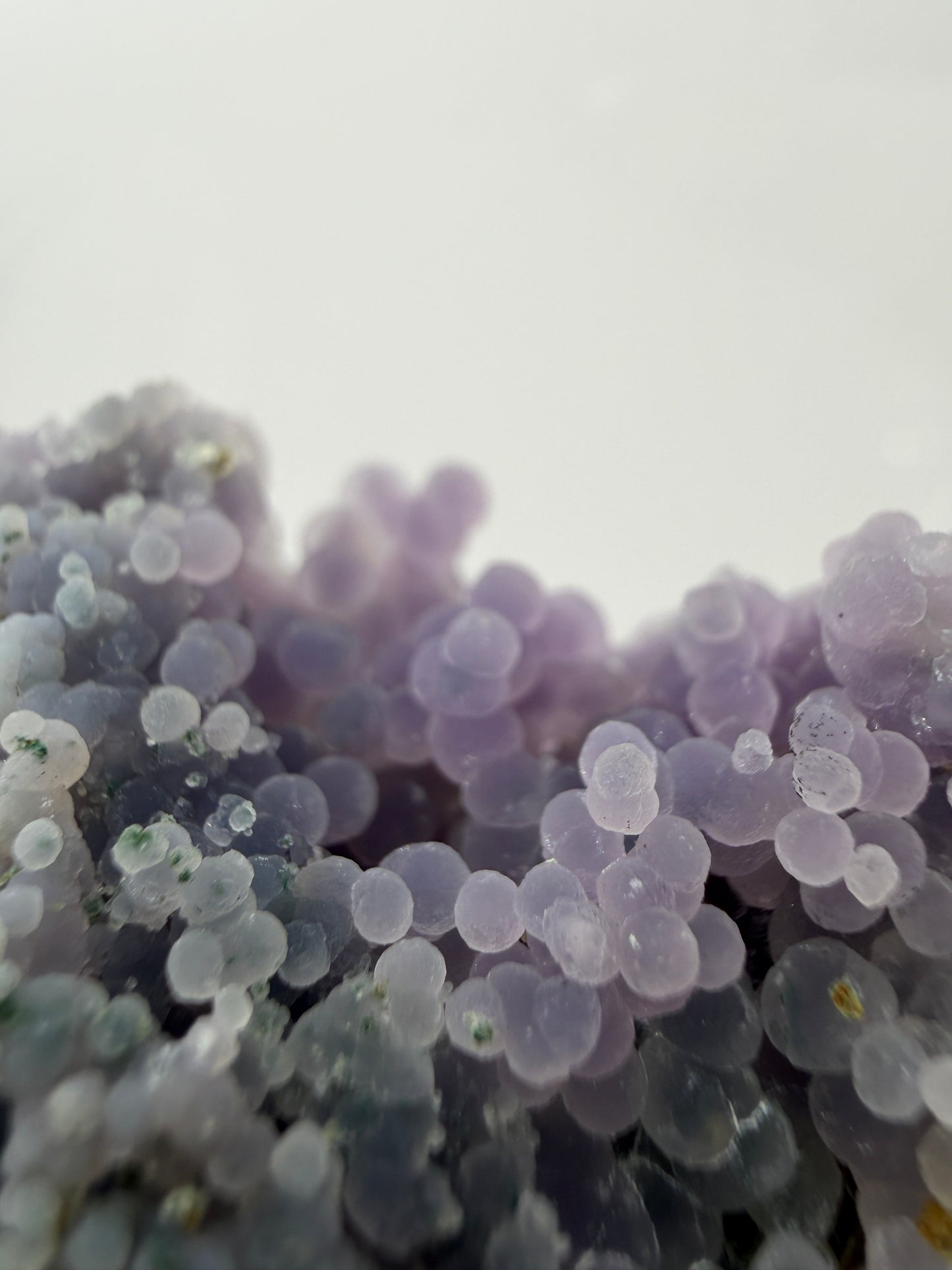 Nahaufnahme der traubenförmigen Struktur von lila Chalcedon, zeigt den glitzernden Drusy-Quarz-Überzug auf den Sphären.