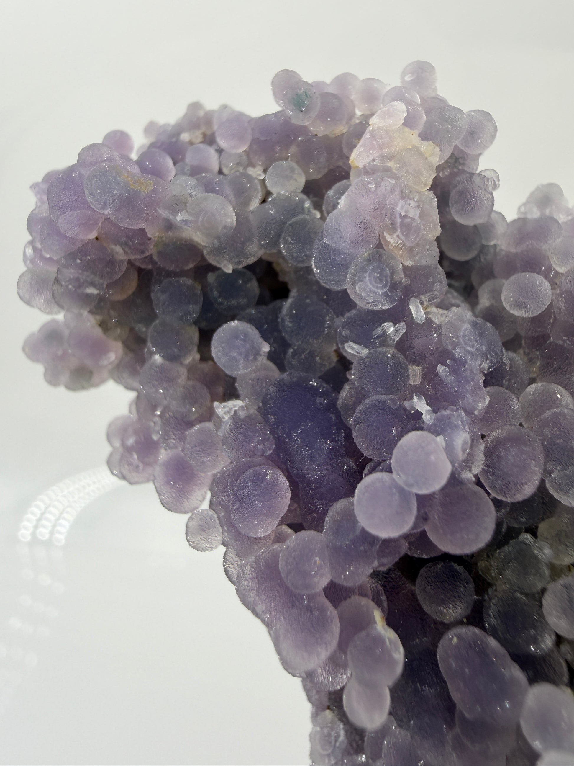 Nahaufnahme der traubenförmigen Struktur von lila Chalcedon, zeigt den glitzernden Drusy-Quarz-Überzug auf den Sphären.