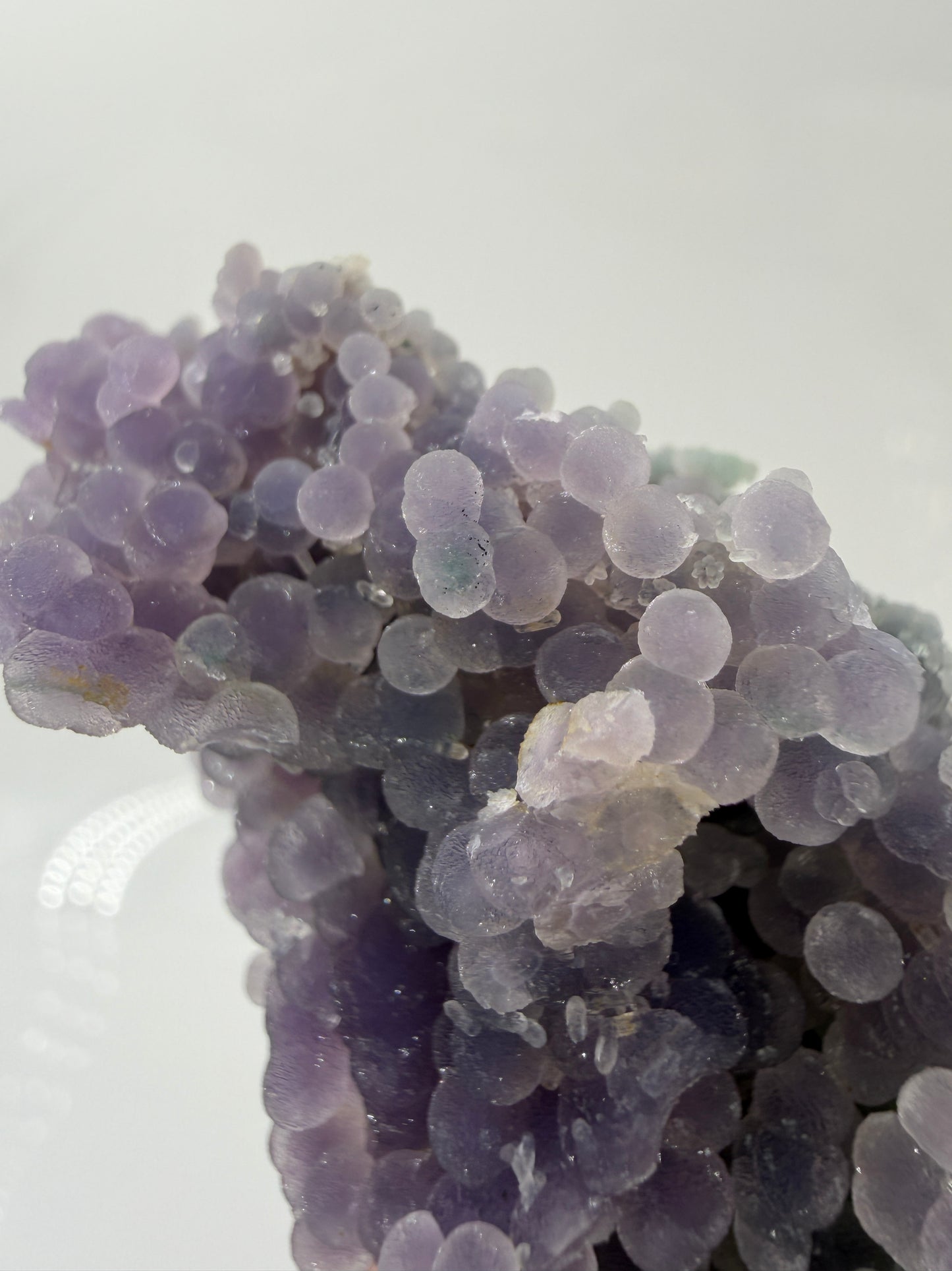 Nahaufnahme der traubenförmigen Struktur von lila Chalcedon, zeigt den glitzernden Drusy-Quarz-Überzug auf den Sphären.