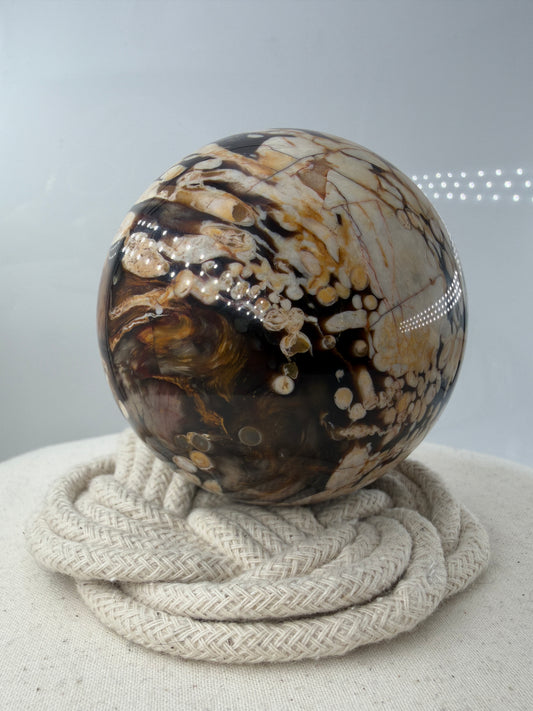 Peanut Jasper Kugel, poliertes versteinertes Holz mit kontrastreichen hellen Einschlüssen fossiler Bohrkanäle.