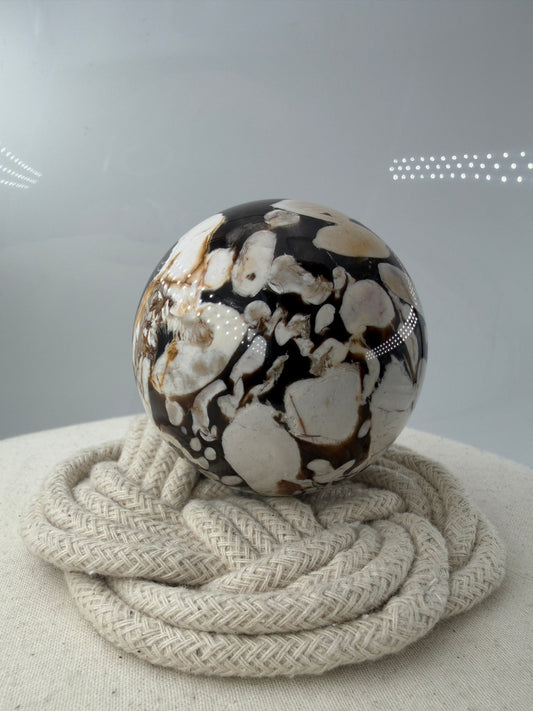 Peanut Jasper Kugel, poliertes versteinertes Holz mit kontrastreichen hellen Einschlüssen fossiler Bohrkanäle.