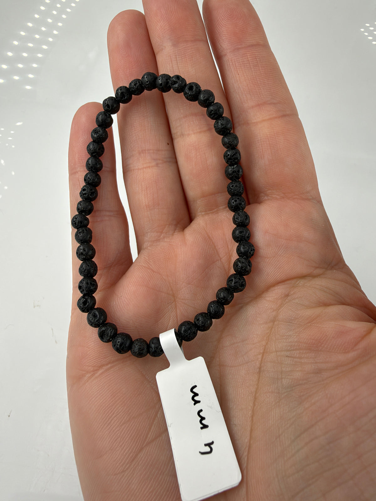 ulkangestein-Armband LG5 mit schwarzen 4-mm-Kugelperlen auf einer offenen Hand.