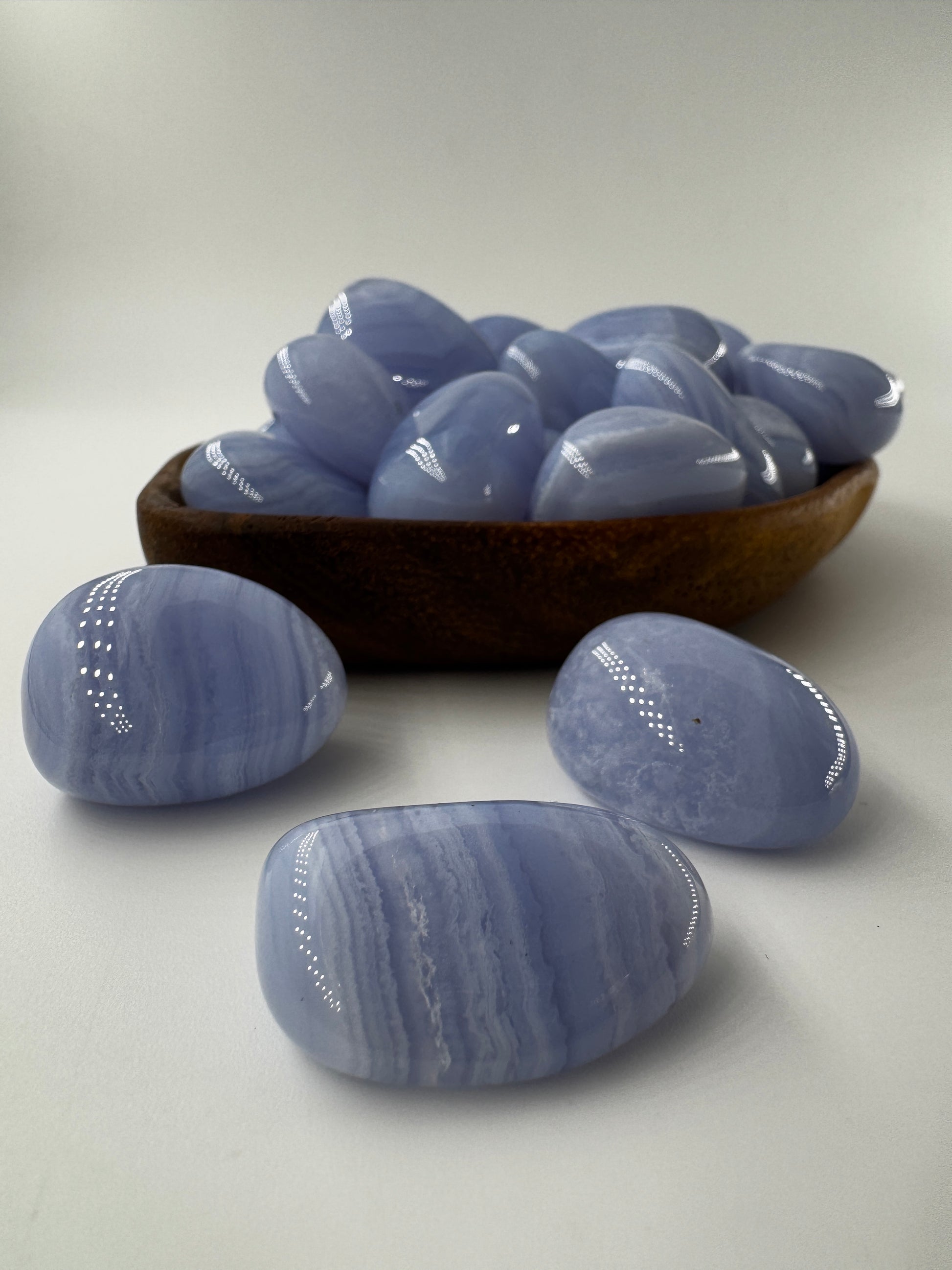 Ein Blue Lace Chalcedon Trommelstein mit seiner charakteristisch hellblauen Bänderung mit feinen weißen Linien und Wölkchen.