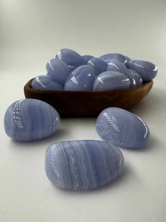 Ein Blue Lace Chalcedon Trommelstein mit seiner charakteristisch hellblauen Bänderung mit feinen weißen Linien und Wölkchen.
