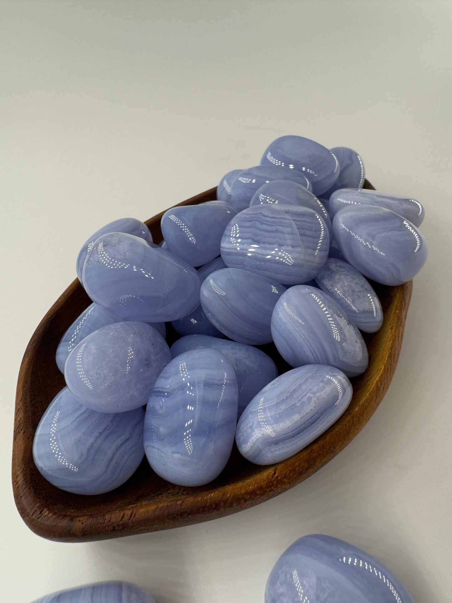 Ein Blue Lace Chalcedon Trommelstein mit seiner charakteristisch hellblauen Bänderung mit feinen weißen Linien und Wölkchen.