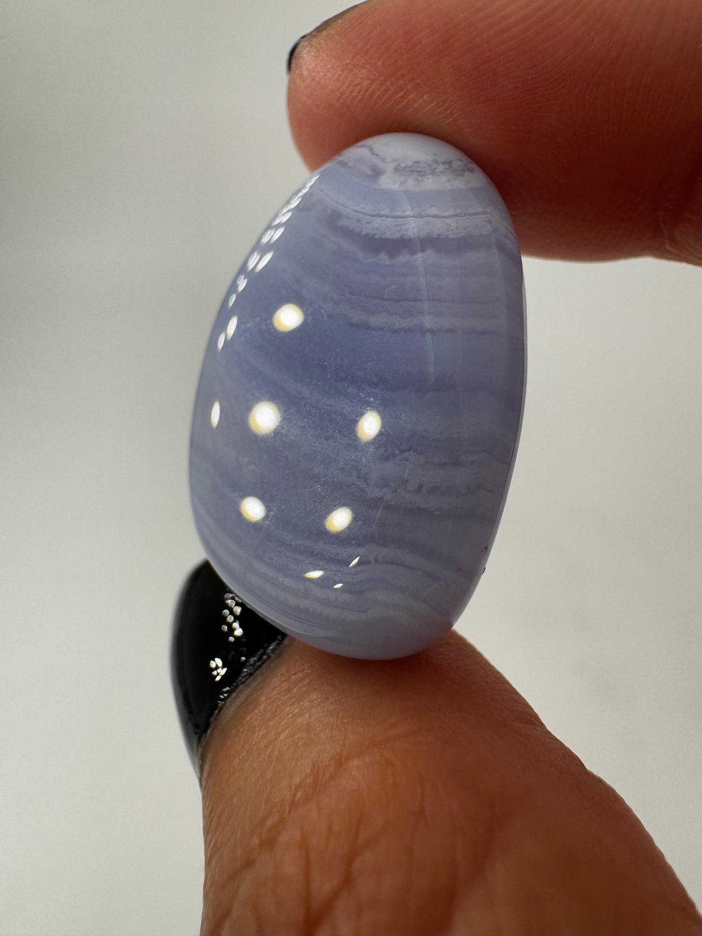 Ein Blue Lace Chalcedon Trommelstein mit seiner charakteristisch hellblauen Bänderung mit feinen weißen Linien und Wölkchen.