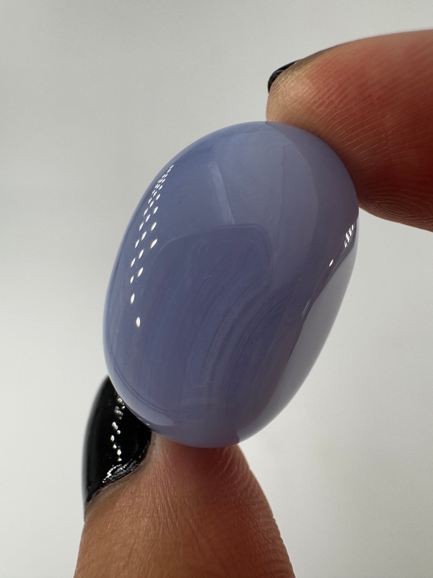 Ein Blue Lace Chalcedon Trommelstein mit seiner charakteristisch hellblauen Bänderung mit feinen weißen Linien und Wölkchen.