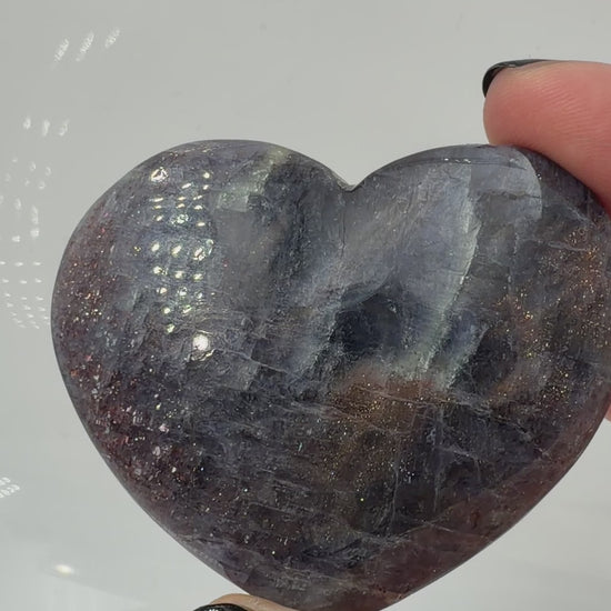 Ein Herz aus dunkelblauem Iolith, mit Sonnenstein. Die glatte Oberfläche zeigt je nach Lichteinfall einen metallischen Glanz und die charakteristischen Farbumschläge der beiden Mineralvarianten.