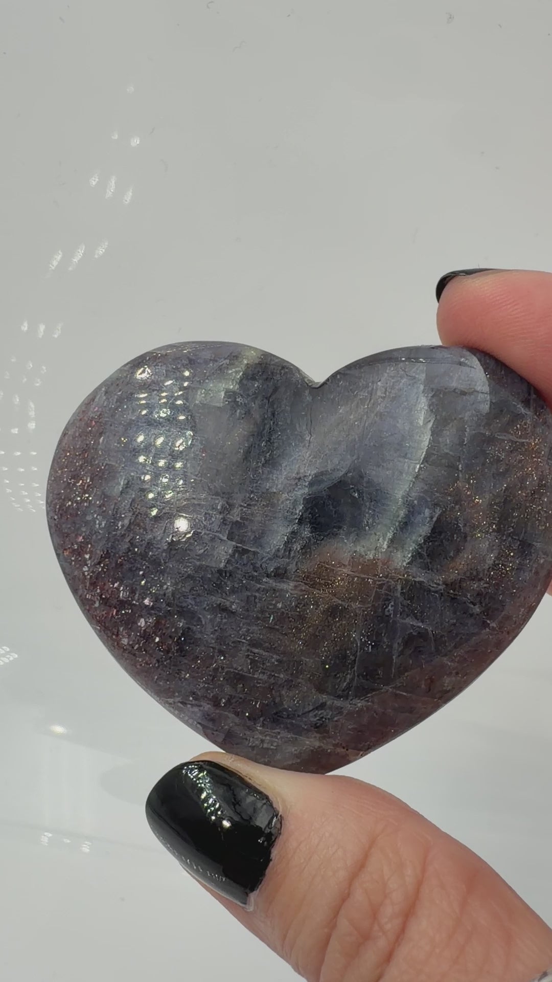 Ein Herz aus dunkelblauem Iolith, mit Sonnenstein. Die glatte Oberfläche zeigt je nach Lichteinfall einen metallischen Glanz und die charakteristischen Farbumschläge der beiden Mineralvarianten.