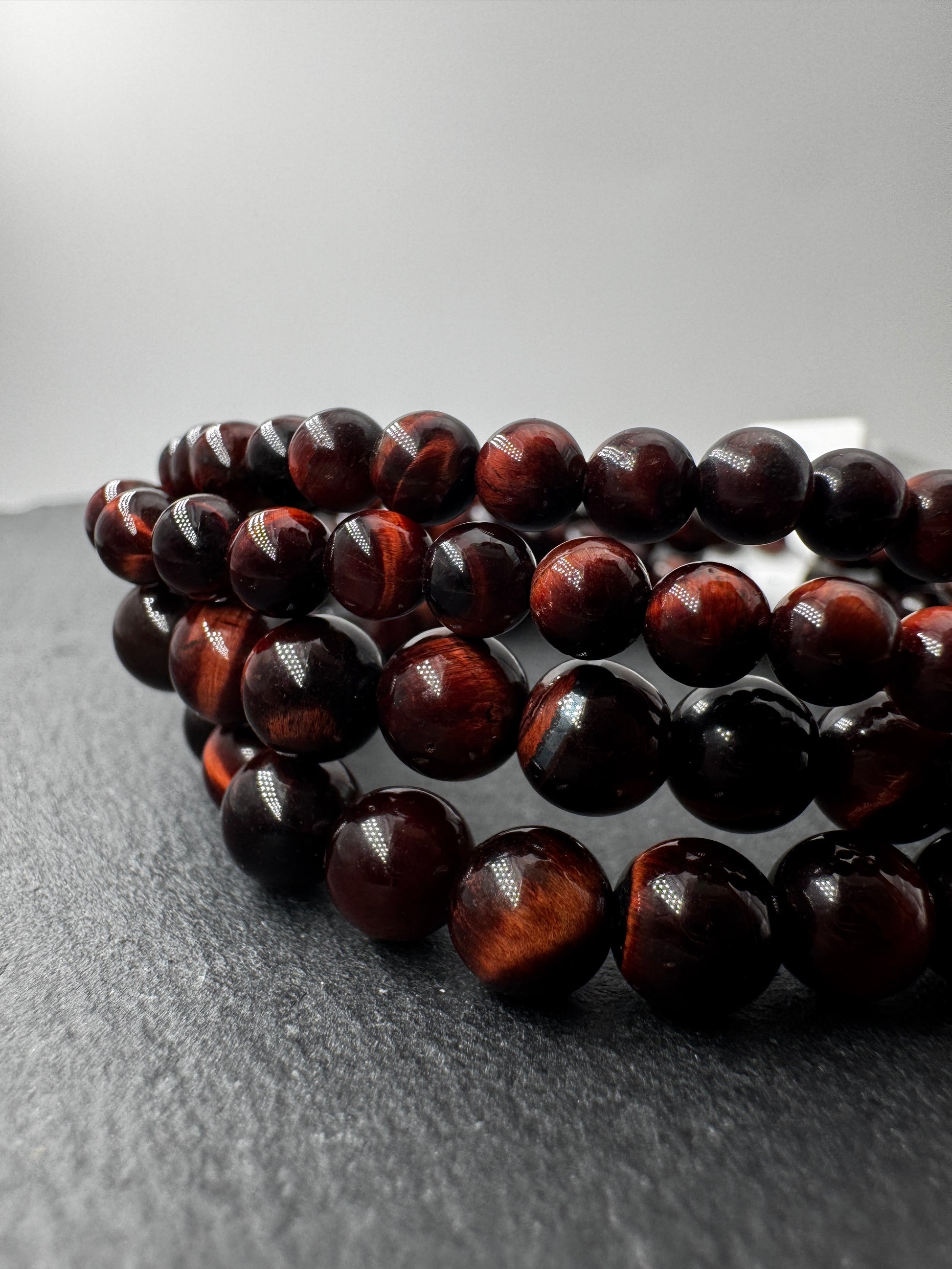 Nahaufnahme eines Kugelarmbands aus rotem Tigerauge mit glänzend polierten Perlen in tiefen Rot- und Brauntönen.