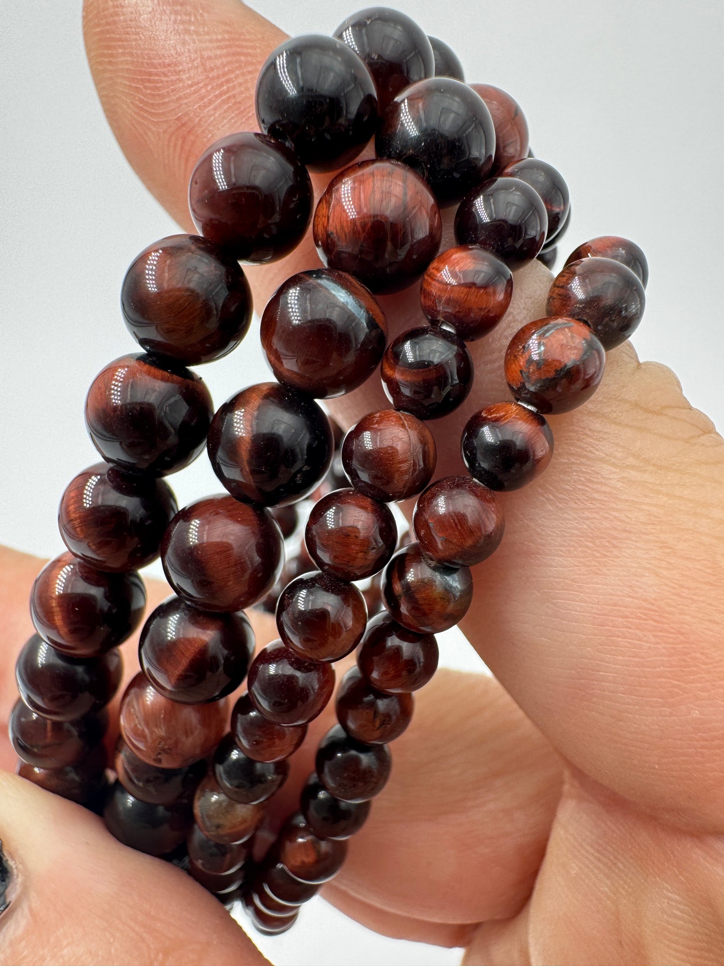 Nahaufnahme eines Kugelarmbands aus rotem Tigerauge mit glänzend polierten Perlen in tiefen Rot- und Brauntönen.