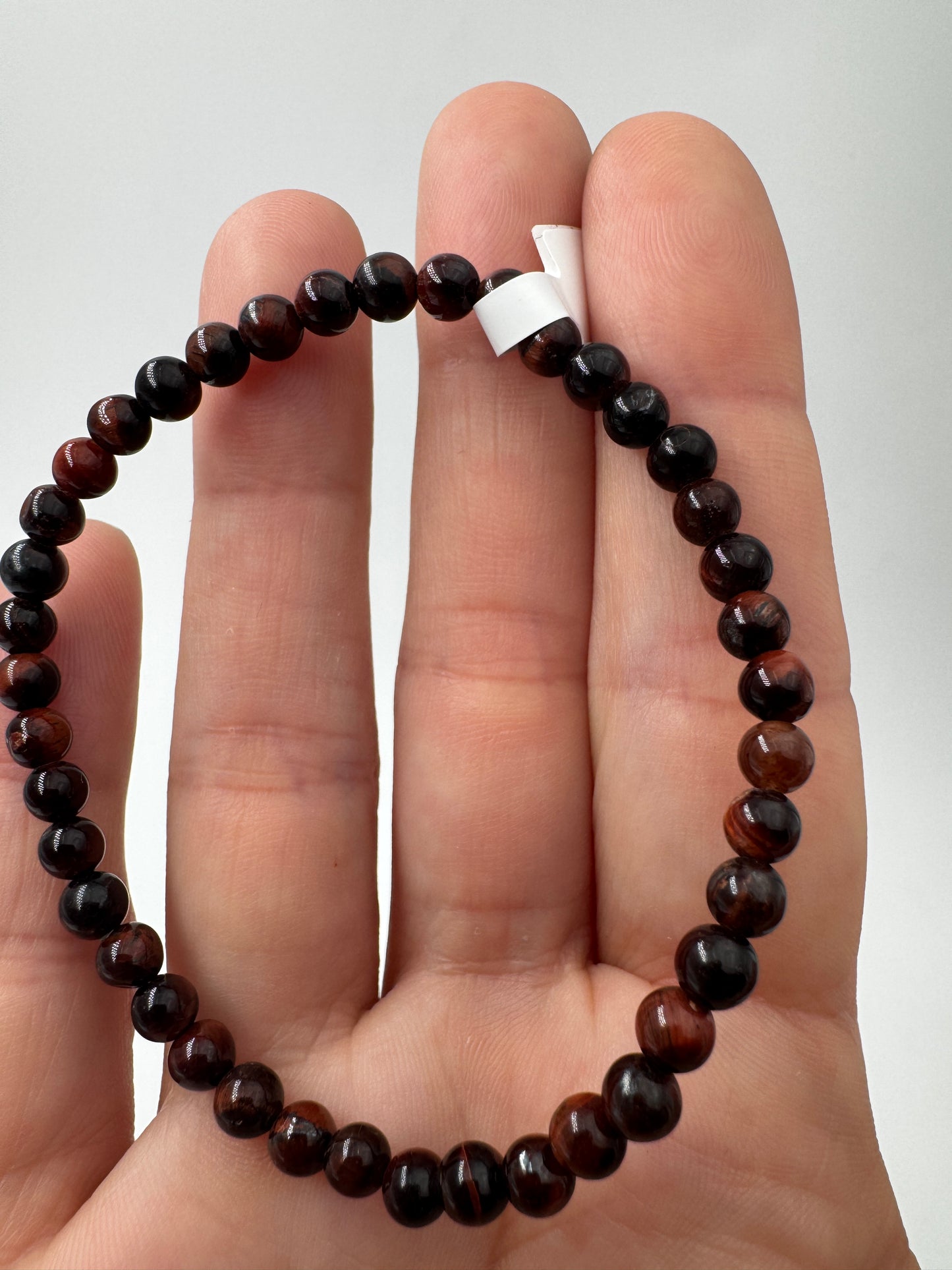 Nahaufnahme eines Kugelarmbands aus rotem Tigerauge mit glänzend polierten Perlen in tiefen Rot- und Brauntönen.